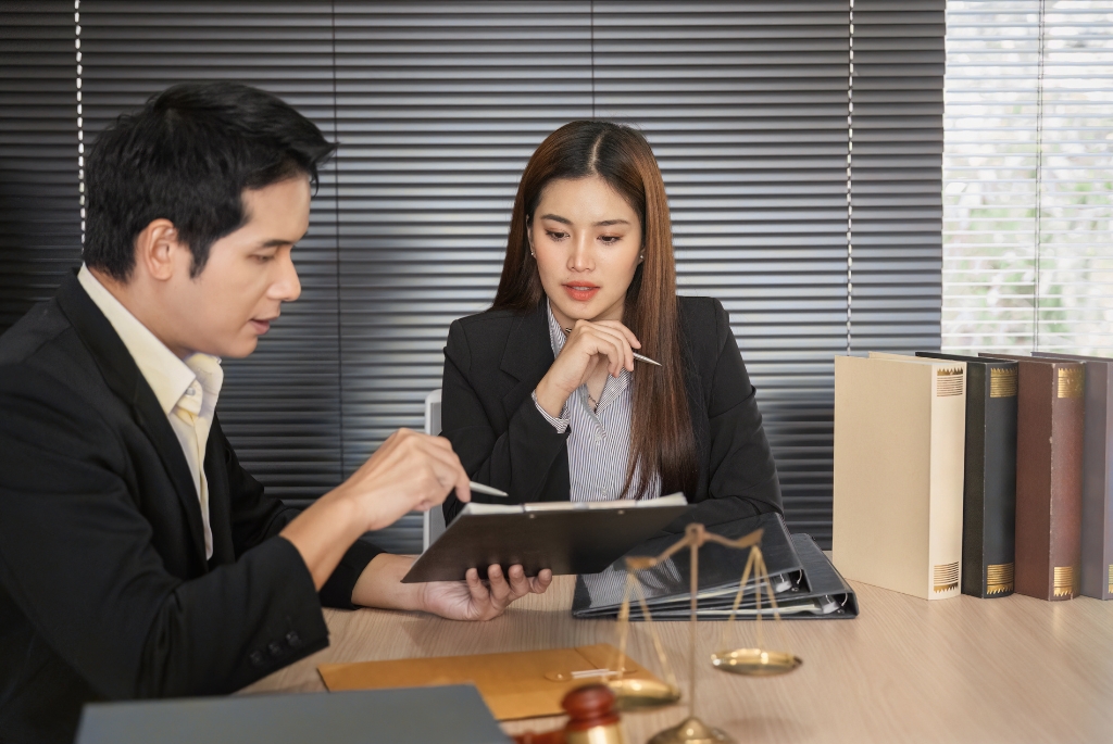 Man helping woman find legal assistant jobs at a law firm desk