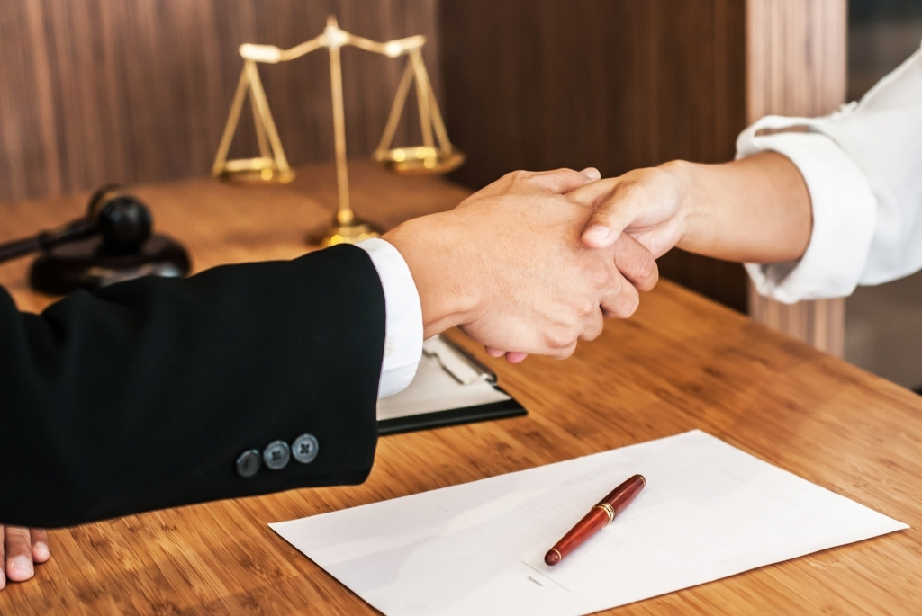 Hands shaking on a lateral hiring deal over table with legal materials